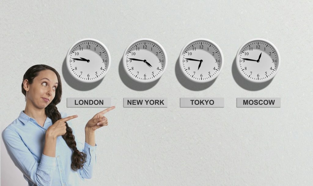 a woman pointing at clocks showing different times.